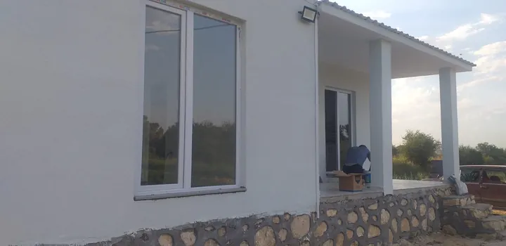 Beyaz cepheli tek katlı yapının verandası ve doğal taş kaplı alt duvarı