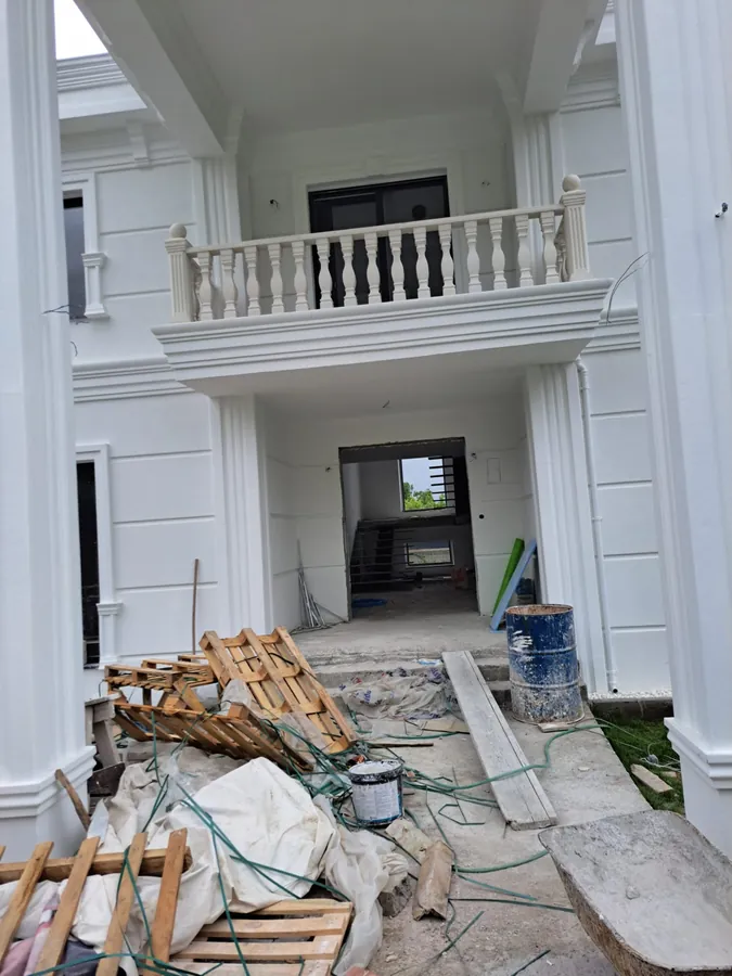 Beyaz sütun ve korkulukları bulunan villa girişinde süren uygulama ve malzeme hazırlığı